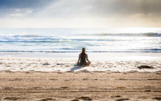 "Woman meditates by the Ocean" by Bestpicko is licensed under CC BY 2.0. To view a copy of this license, visit https://creativecommons.org/licenses/by/2.0/?ref=openverse.